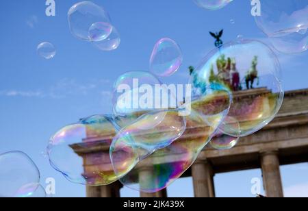 Berlino, Germania. 30th luglio 2022. Un artista di strada attinge bolle di sapone di grandi dimensioni nel cielo di fronte alla porta di Brandeburgo. Credit: Paul Zinken/dpa/Alamy Live News Foto Stock