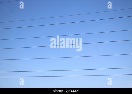 Linee di trasmissione della potenza contro il cielo blu profondo con spazio di copia Foto Stock