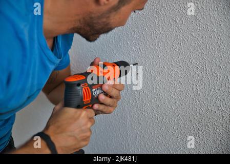 Falegname che lavora con attenzione, uomo che fora un muro. Lavorare a casa. Foto Stock