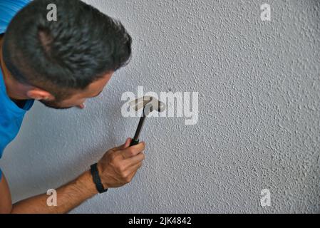 Falegname che lavora con attenzione, uomo martellando un muro. Lavorare a casa. Foto Stock