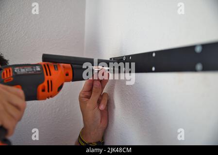 Falegname che lavora con attenzione, uomo che fora un muro. Lavorare a casa. Foto Stock