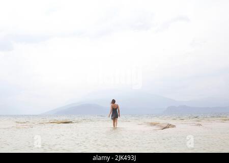 la donna solitaria cammina verso l'infinito in mezzo al mare Foto Stock