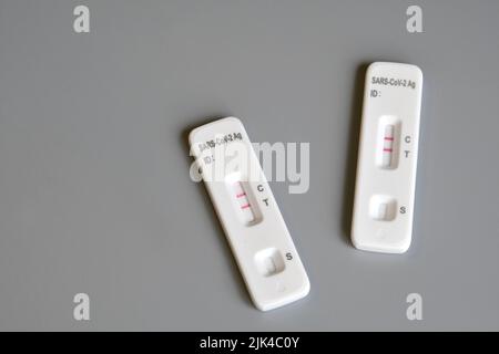 Due kit per test antigenici SARS‑cov‑2 per test automatici con risultati positivi. Test rapido dell'antigene del coronavirus in una fase, tampone saliva su sfondo grigio. Chiudere Foto Stock