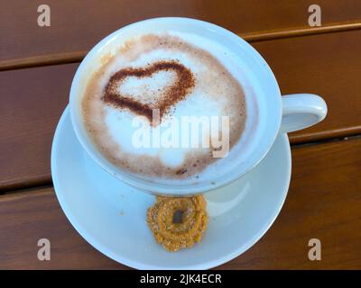 Tasse Cappuccino mit einem Herz aus Kakao verziertem Milchschaum Foto Stock