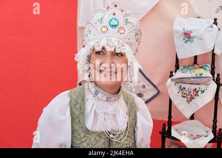 Ritratto di sorridente anziana donna in stilizzato antico headdress russo - kokoshnik in vacanza rurale. Foto Stock