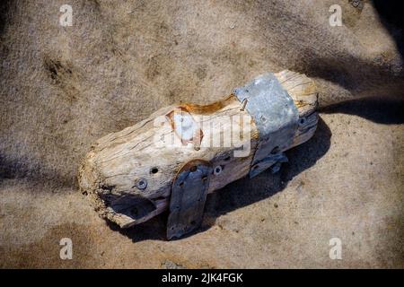 Piccolo pezzo di legno marcio con lavori di metallo da un relitto in un tessuto sfondo. Foto Stock