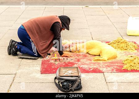 uomo che fa la scultura di sabbia del cane dormiente sul marciapiede in liverpolo Foto Stock