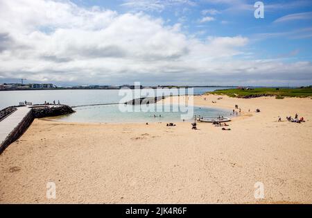 Nauthólsvík, Reykjavik, Islanda: 24JUL2022: Spiaggia geotermica di Nauthólsvík in Islanda nella soleggiata giornata estiva. La gente nuota e si rilassa sulla spiaggia dorata. Foto Stock