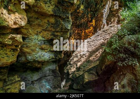 Scogliere di dolomite color giallo-cremoso nella gola di Knaresborough con piani da letto prominenti e un grande masso di pietra calcarea di fronte. Foto Stock