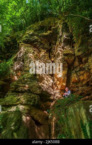 Dominika Wroblewska sotto una scogliera dolomitica sulla cima di un letto di pietra grattugiata, nella gola di Knaresborough, vicino Harrogate, Yorkshire. Foto Stock