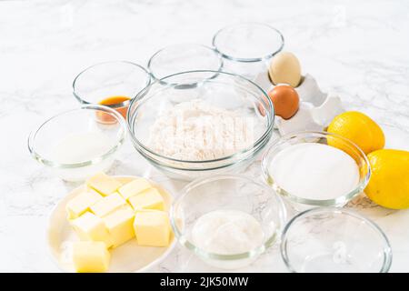 Ingredienti misurati in recipienti di miscelazione in vetro per preparare i cupcake al limone. Foto Stock