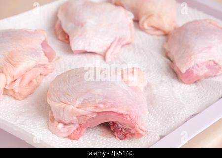 Le cosce di pollo vengono asciugate su un tovagliolo di carta dopo il lavaggio per un ulteriore congelamento. Foto Stock