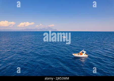 Vista aerea di due barche bianche che navigano attraverso il mare in un bel tempo soleggiato con il Monte Athos sullo sfondo. Foto di alta qualità Foto Stock