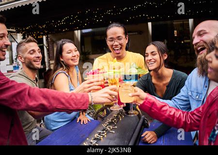 Divertente gruppo multiculturale di amici che si godono drink serali al Bar. Persone che si divertono insieme Foto Stock