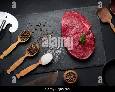 Filetto di manzo crudo si trova su una tavola, tavola nera. Vista dall'alto Foto Stock