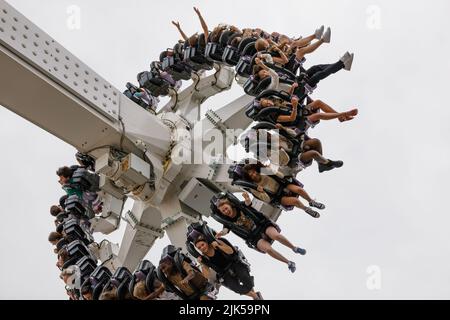 Un giro a pendolo con giovani, gambe penzolanti, braccia nell'aria, sorridenti ed eccitati Foto Stock