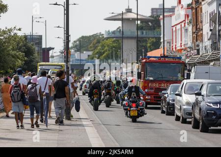 Heatwave Inghilterra. Congestione del traffico con ciclisti, auto e motore antincendio su una strada trafficata e pedoni che camminano in una calda giornata estiva in un mare inglese Foto Stock