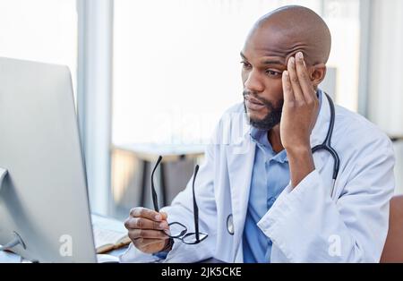 Non dimenticate di prendervi cura di voi stessi, un giovane medico che soffre di mal di testa sul lavoro. Foto Stock