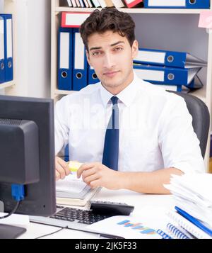 Imprenditore lavora in ufficio con pile di libri e giornali facendo di documenti cartacei Foto Stock