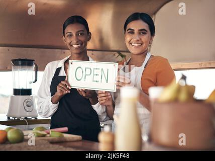 Due giovani donne d'affari che hanno un segno aperto nel loro camion del cibo. Foto Stock