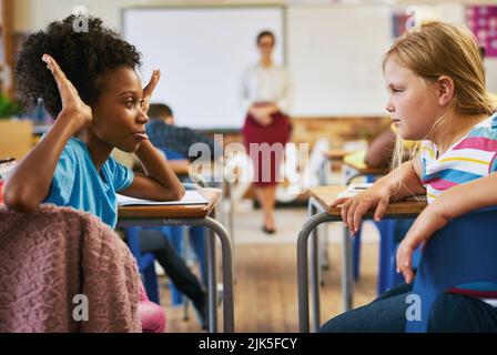 Il bullismo deve essere fermato, una ragazza che siede in aula a scuola e che sdraia il suo compagno di classe. Foto Stock