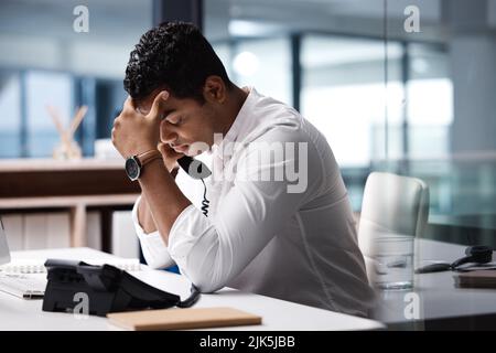 A volte è sufficiente lasciare che il cliente si ramboli. Un giovane uomo d'affari che guarda stressato mentre parla al telefono in ufficio. Foto Stock