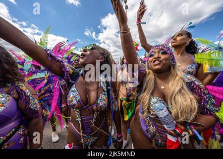 Toronto, Canada. 30th luglio 2022. I partecipanti alla sfilata vestiti con abiti colorati e piume tengono le mani e i telefoni cellulari a un galleggiante durante il festival in luogo eshibitino. Dopo due anni di blocco dalla pandemia del convivio-19, il Carnevale dei Caraibi di Toronto ritorna con la Grand Parade. Credit: SOPA Images Limited/Alamy Live News Foto Stock