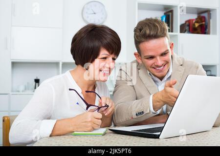 Mamma e figlio adulti considerano il software sul laptop Foto Stock