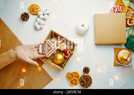 Vista dall'alto della mano della donna con casa di pan di zenzero. Foto Stock