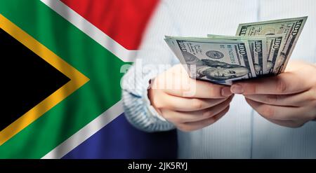 Mani detiene americano 100 dollari banconota e bandiera del Sud Africa primo piano Foto Stock