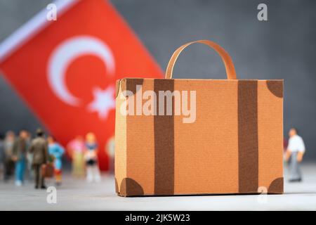 Valigia di cartone, giocattolo di plastica e una bandiera su uno sfondo astratto, un concetto sul tema del trasferimento o migrazione in Turchia Foto Stock