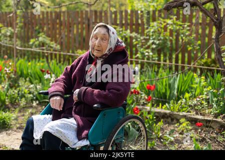 Donna anziana seduta su una sedia a rotelle che sembra triste e preoccupato: Depressione, assistenza sanitaria e cura per gli anziani Foto Stock
