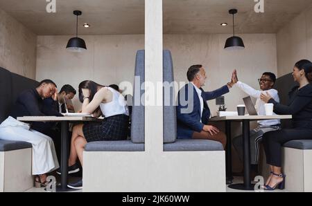 Gli alti e i bassi di essere nel commercio. Un gruppo dei colleghe che lavorano insieme in un armadio del caffè. Foto Stock