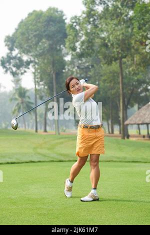 Donna vietnamita di mezza età che gioca a golf nel club Foto Stock