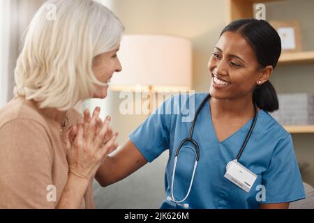 Volevo darti le buone notizie di persona, un medico che ha una consulenza con una donna anziana a casa. Foto Stock