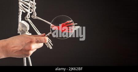 Banner con mano con lente d'ingrandimento su ossa carpale di scheletro umano con punta rossa. Dolore al polso. Mollo del braccio, frattura. Concetto di studio anatomico. Spazio di copia. Foto di alta qualità Foto Stock