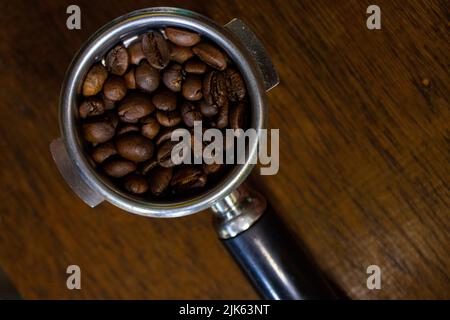 filtro porta con caffè macinato e chicchi di caffè sul tavolo Foto Stock