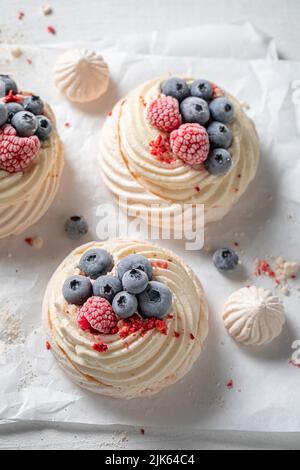Dessert Pavlova fatto in casa e gustoso con frutti di bosco freschi e meringa. Mini dessert Pavlova con lamponi e mirtilli. Foto Stock