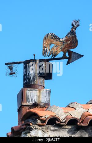 Pentola di Chimney di metallo e paletta di tempo nella forma di un cockerel di crowing, in cima ad una casa nel piccolo villaggio di Agios Germanos vicino al lago di Prespa nel Pre Foto Stock