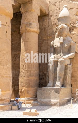 Luxor, Egitto; 28 luglio 2022 - un uomo arabo siede all'ingresso del Tempio di Luxor, Egitto. Foto Stock