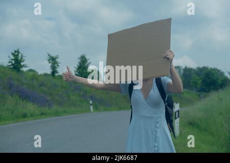 ragazza viaggia hitchhiking. Close up ragazza viaggia hitchhiking con un segno di cartone nelle sue mani Foto Stock