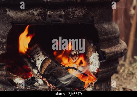 Legno che brucia. Il resto dell'alveare. Legna da ardere. Ceneri nel cavoldro. Resti del fuoco. Foto Stock