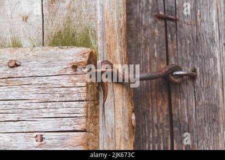 Vecchio bullone. Castello d'epoca. Porta su un gancio. Vecchia recinzione in legno. Territorio chiuso. Foto Stock