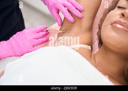 Il paziente giovane riceve le iniezioni nell'area delle ascelle Foto Stock