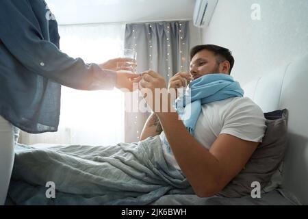 Il ragazzo nella sciarpa prende la medicina per l'influenza Foto Stock