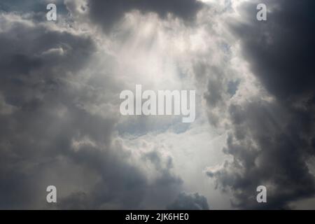 Nuvole tempesta che si radunano con raggi del sole che si infrangono Foto Stock