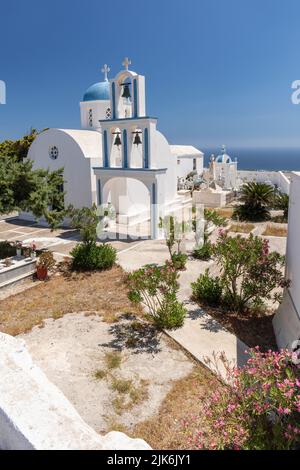 Bella chiesetta bianca con cupola blu, campanile e cimitero. A pochi metri dalla Chiesa di Agios Charalambos, Exo Gonia Santorini, Grecia. Foto Stock