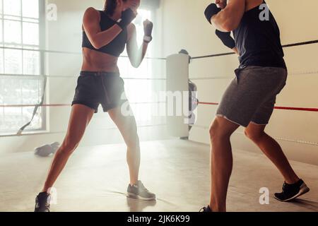 Due giovani lottatori che si affrontano senza guanti in un anello di pugilato. Due giovani pugili che si scatenano durante una sessione di allenamento in una palestra di boxe. Foto Stock