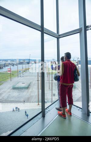 I turisti scattano fotografie dall'interno dell'attrazione turistica Titanic Belfast della slitta Titanic, Belfast, Irlanda del Nord, Regno Unito Foto Stock