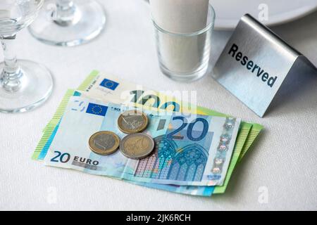 Moneta dell'Unione europea su un tavolo con ricevuta, bicchieri da vino, piatto in ristorante in Europa Foto Stock